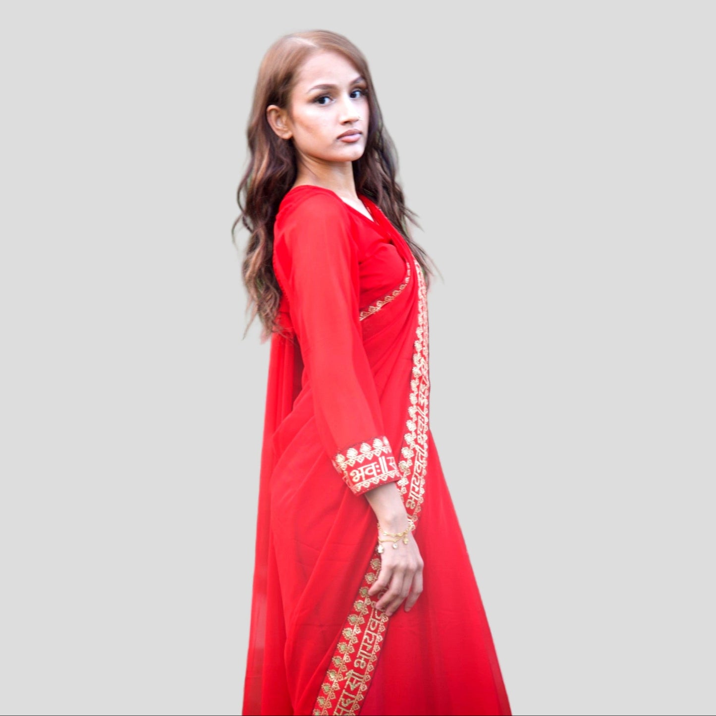 Woman wearing a red traditional outfit with gold embroidery on a gray background