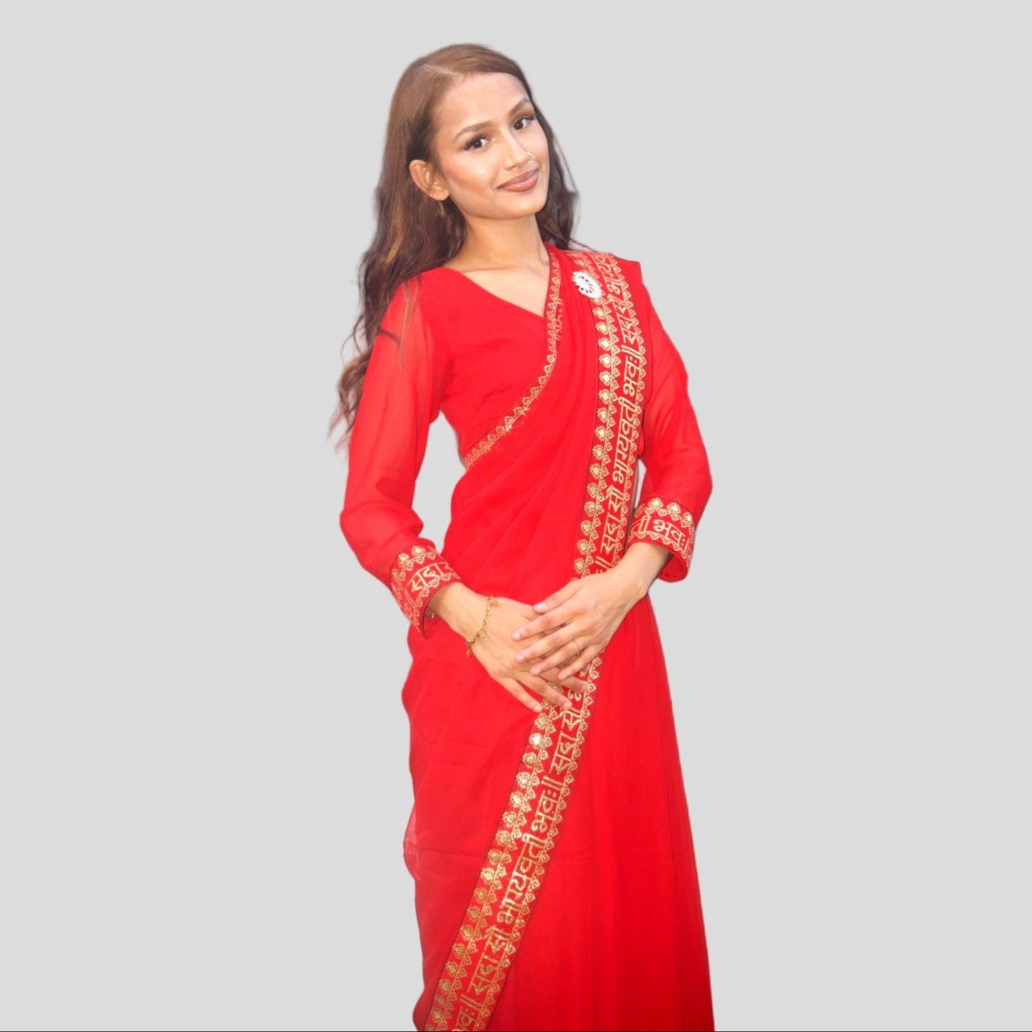 Woman wearing a red saree with gold embroidery on a gray background