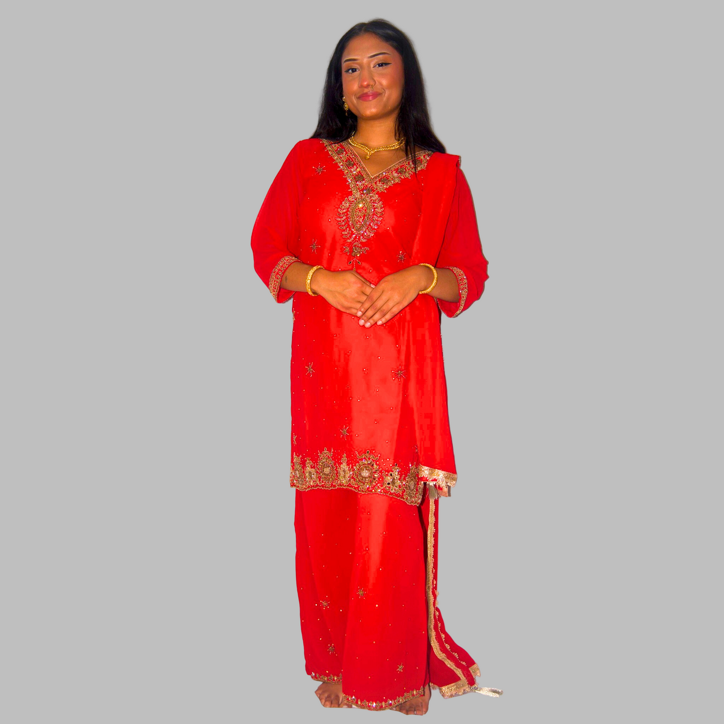 Woman wearing a red traditional outfit with gold embroidery on a white background