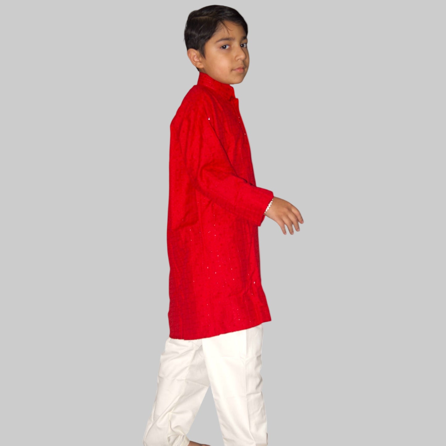 Child wearing a red kurta with white pants on a white background