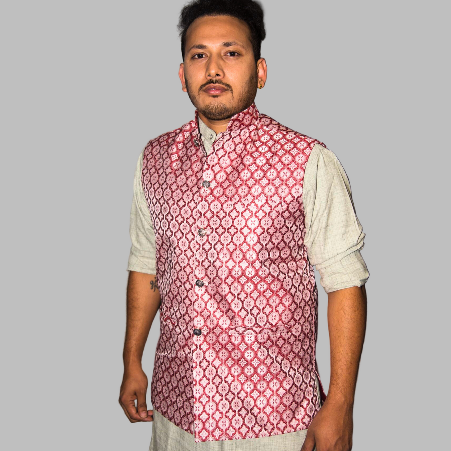 Man wearing a red patterned vest over a light shirt against a plain background
