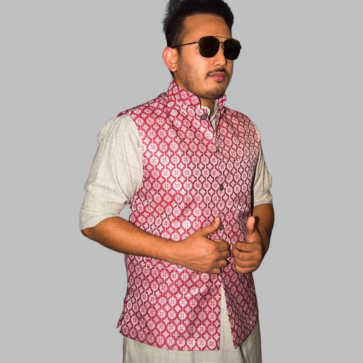 Man wearing a red patterned vest over a light shirt against a plain background