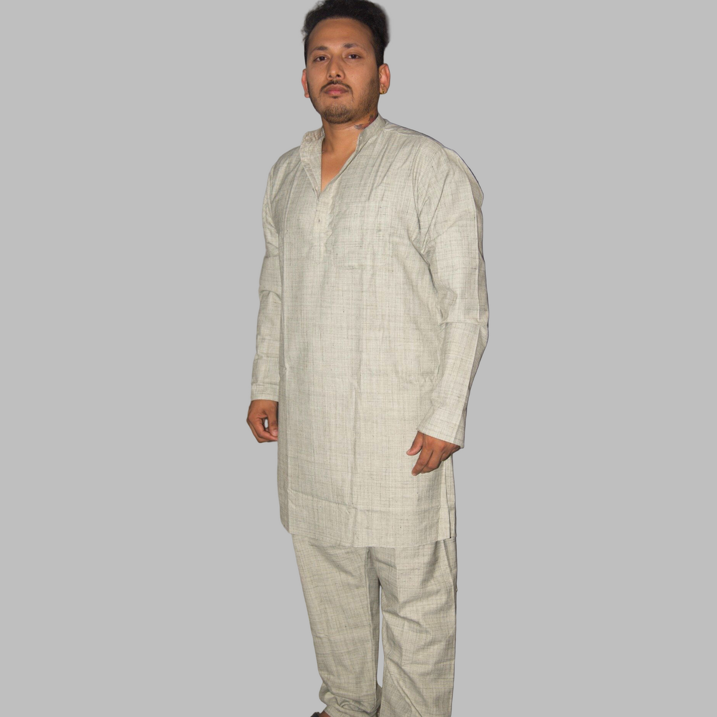 Man wearing a light-colored traditional outfit against a plain background