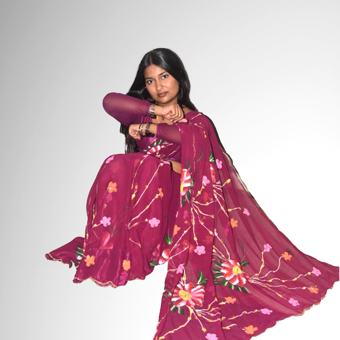 Woman wearing a dark purple saree with floral patterns on a plain background