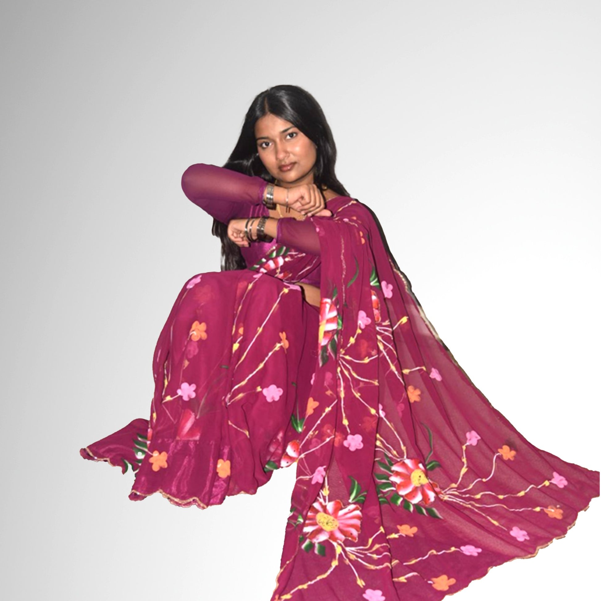 Woman wearing a dark purple saree with floral patterns on a plain background