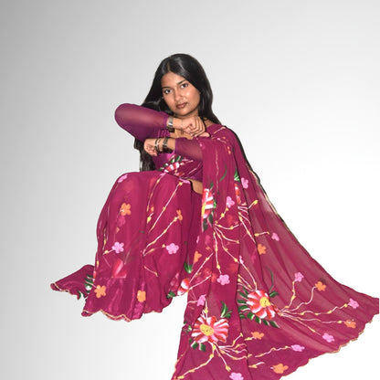 Woman wearing a dark purple saree with floral patterns on a plain background