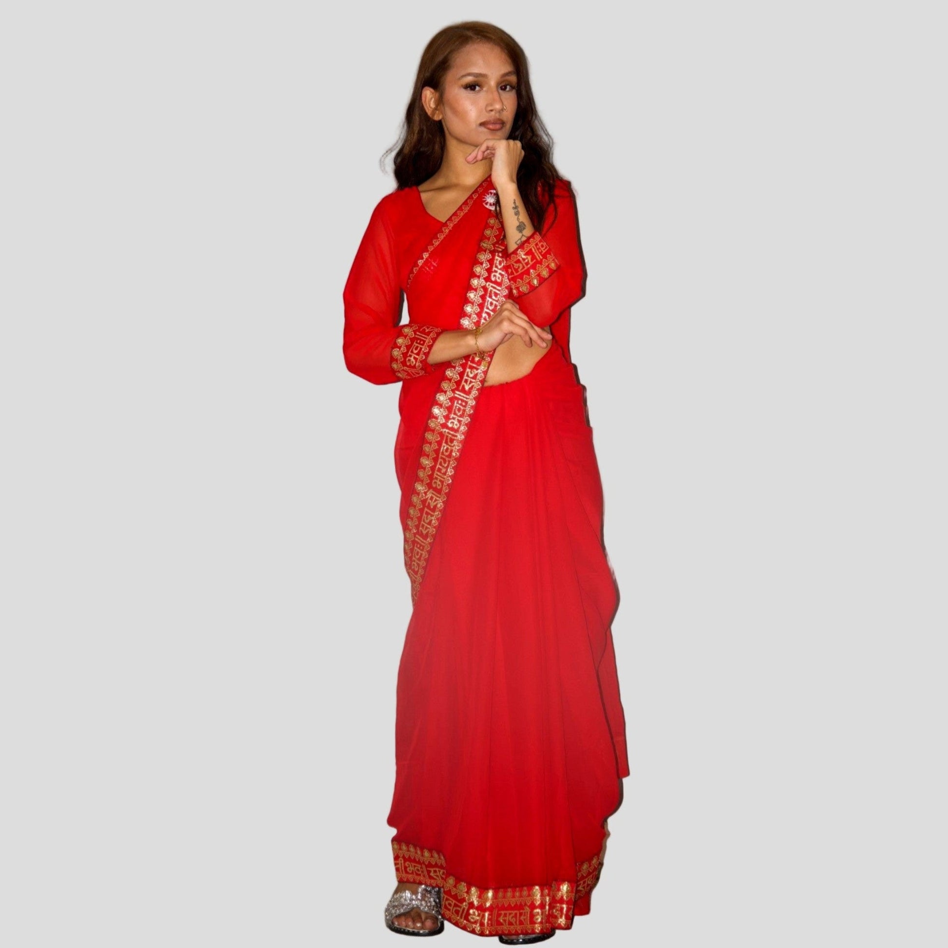 Woman wearing a red saree with a white border on a gray background