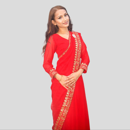 Woman wearing a red saree with gold embroidery on a gray background
