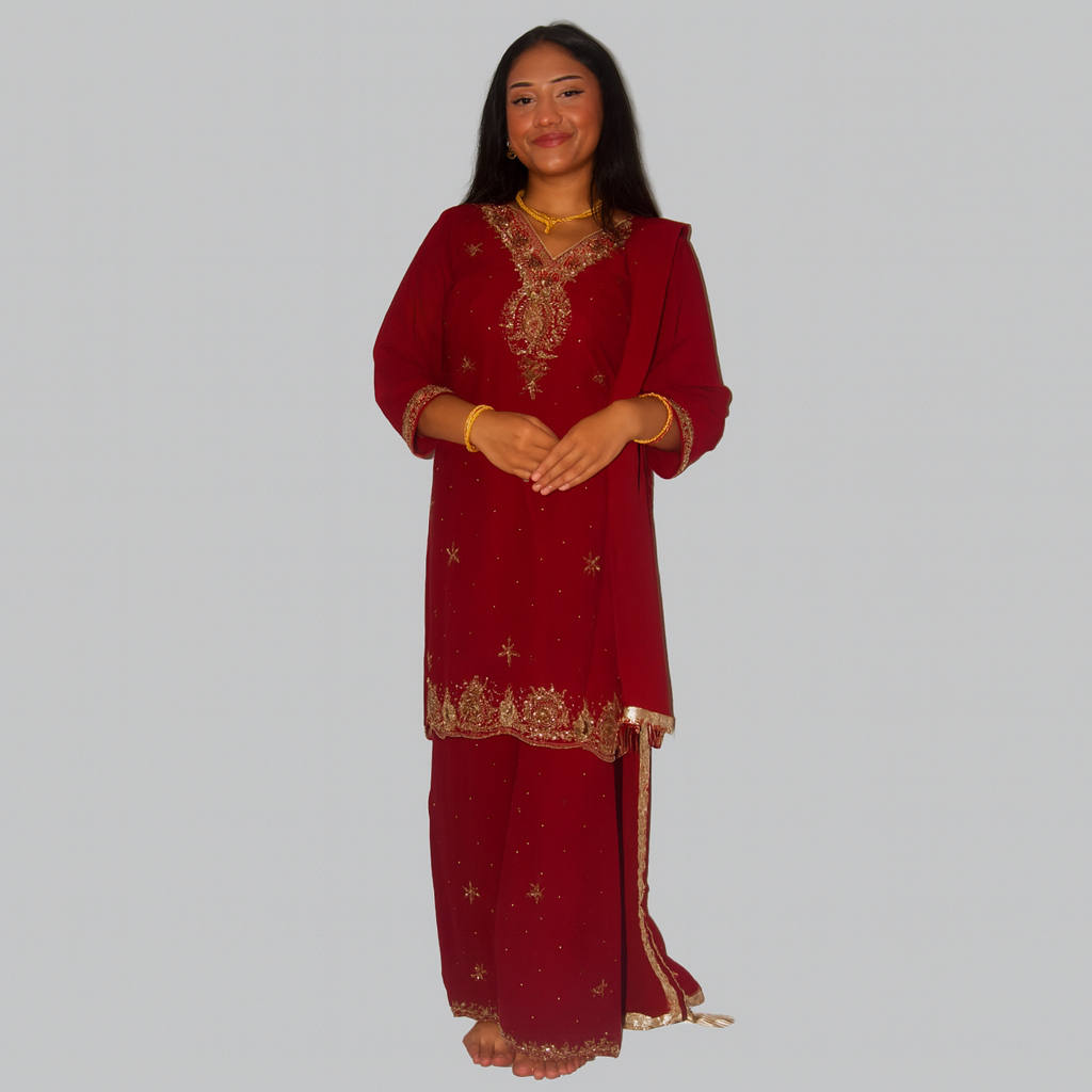 Woman wearing a red traditional outfit with gold embroidery on a plain background