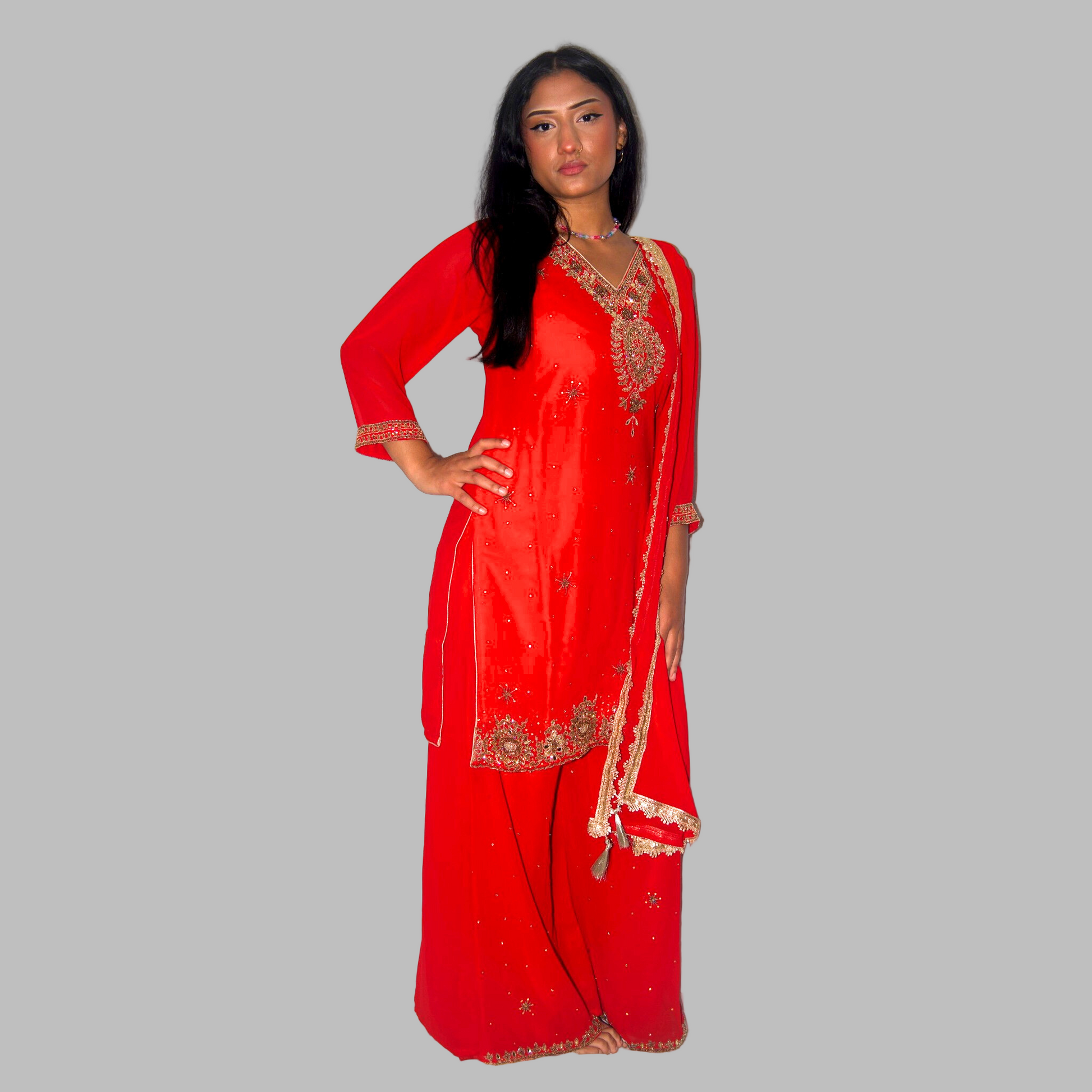 Woman wearing a red traditional outfit with gold embroidery on a white background