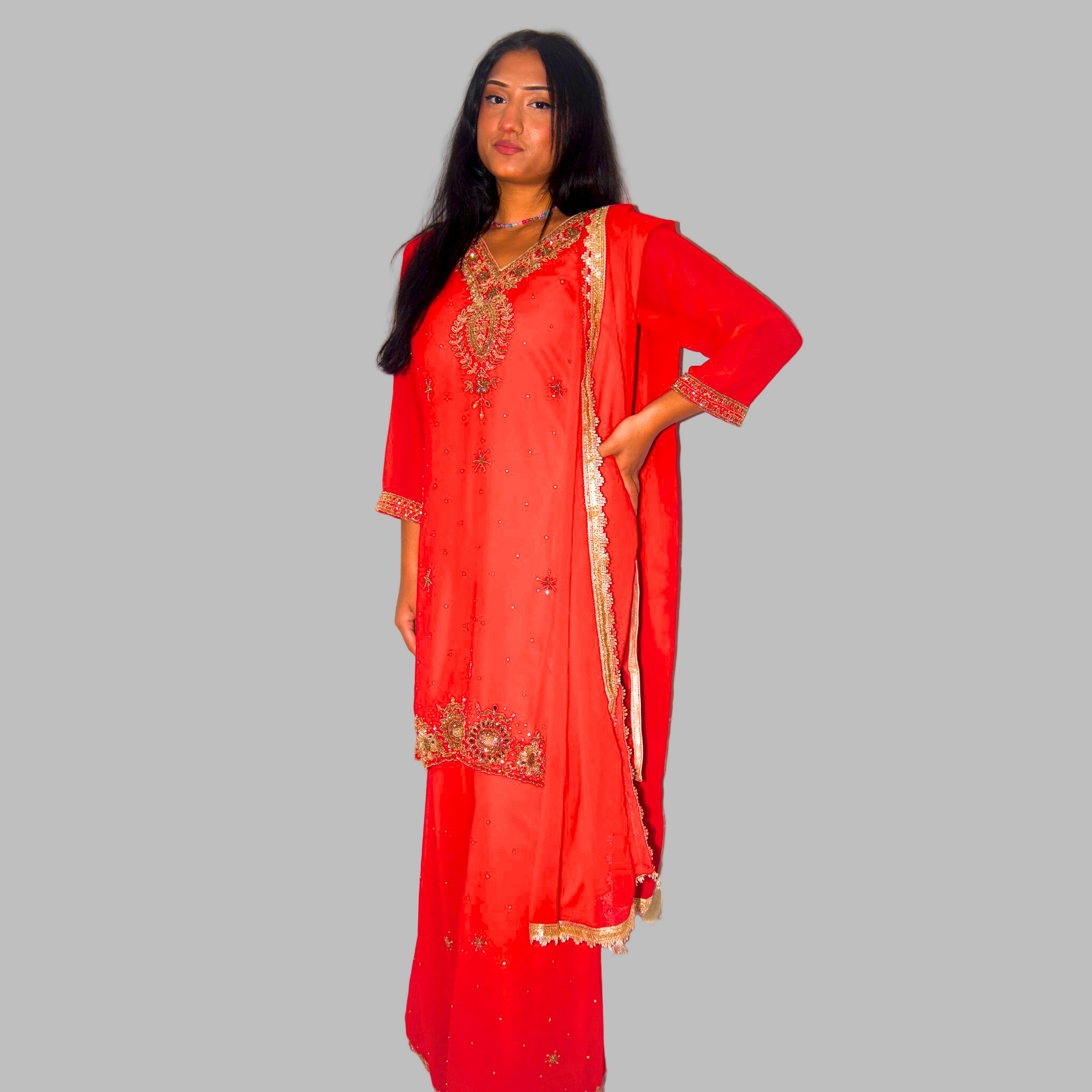 Woman wearing a red traditional outfit with gold embroidery on a white background