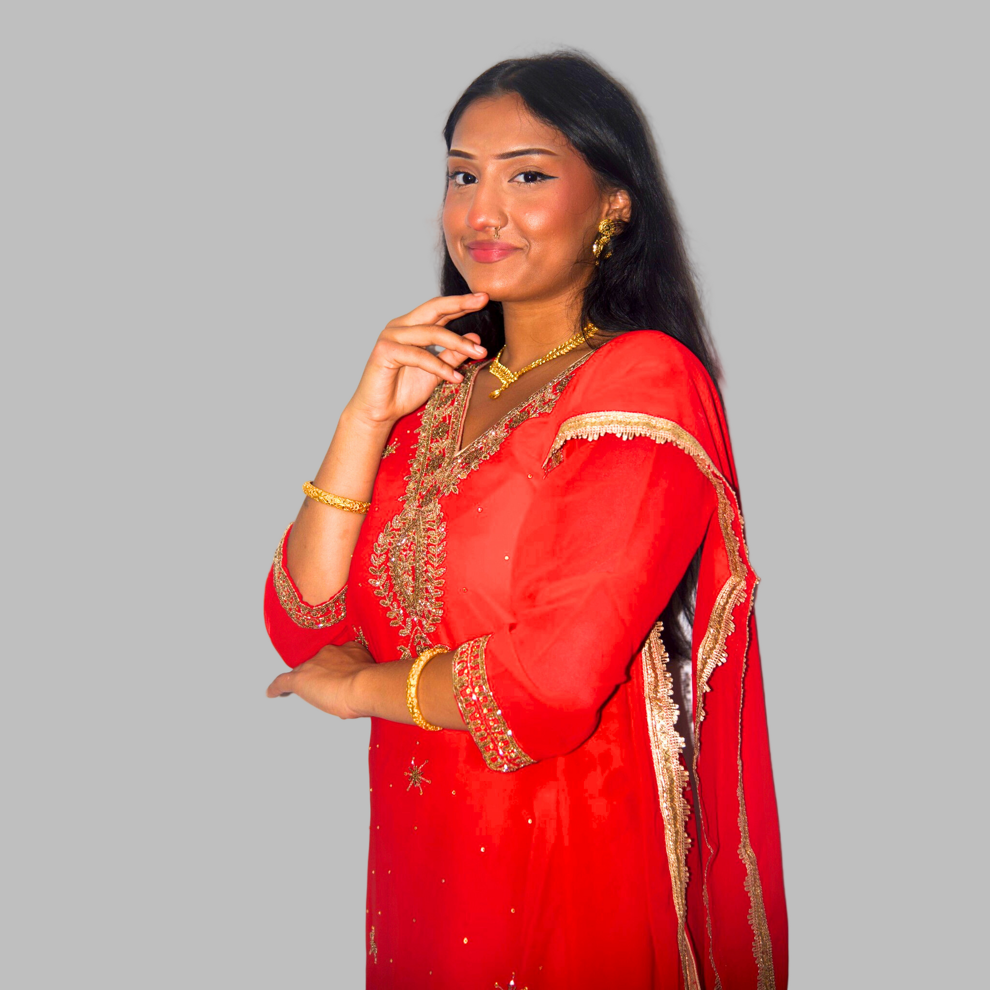 Woman wearing a red traditional outfit with gold embroidery on a white background