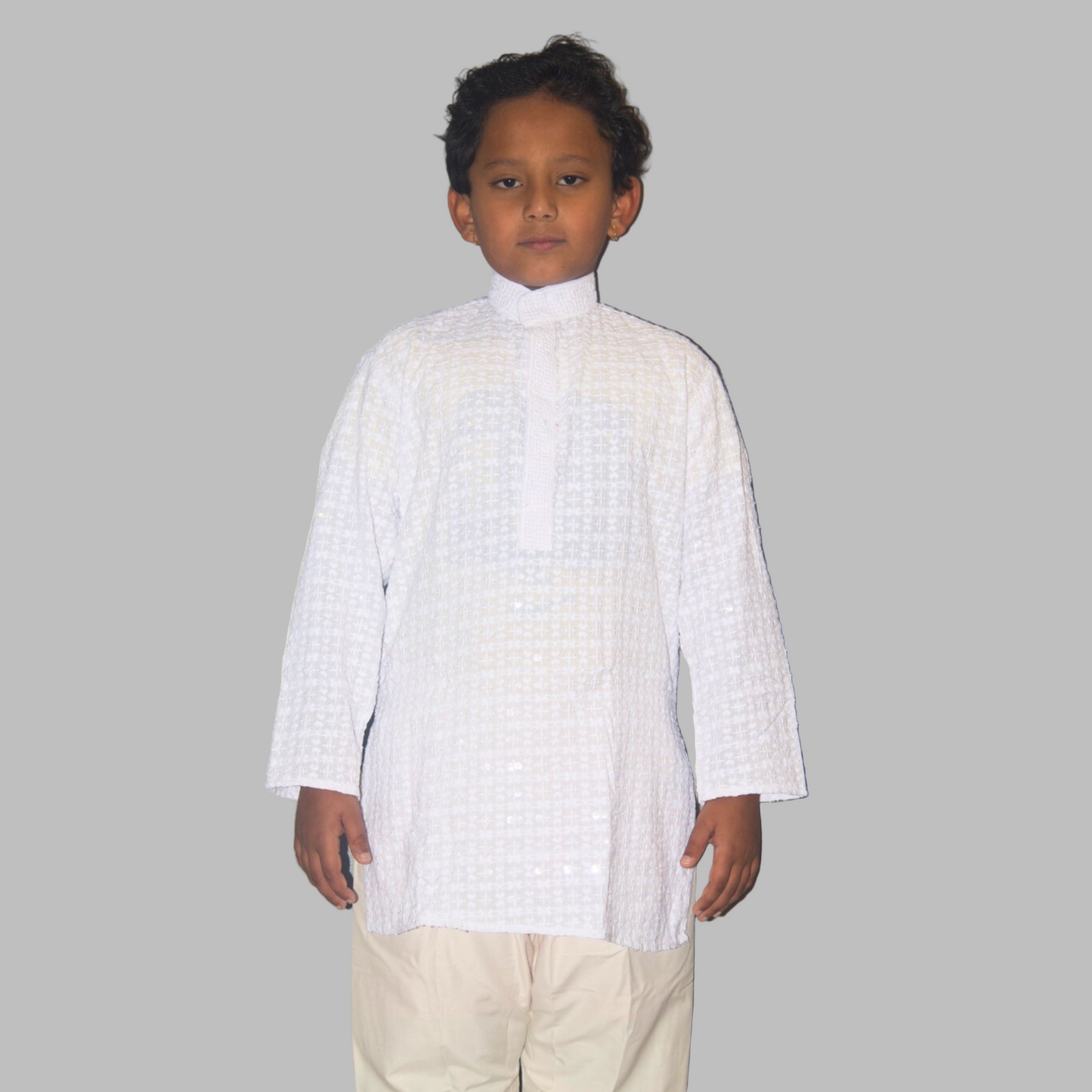 Child wearing a white traditional outfit against a plain background