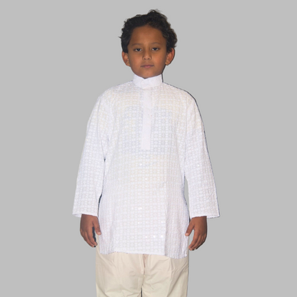 Child wearing a white traditional outfit against a plain background