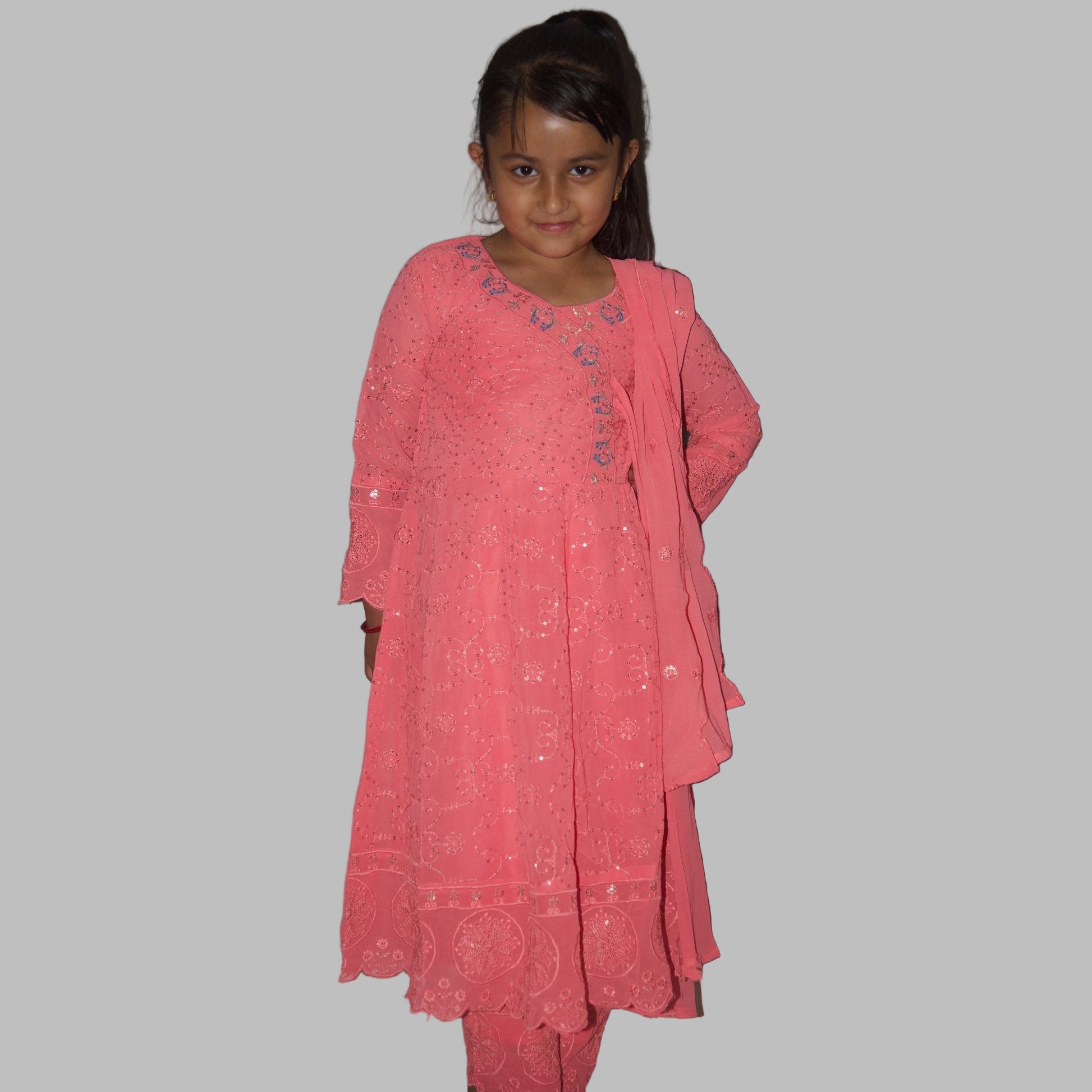 Young girl wearing a pink traditional outfit against a plain background