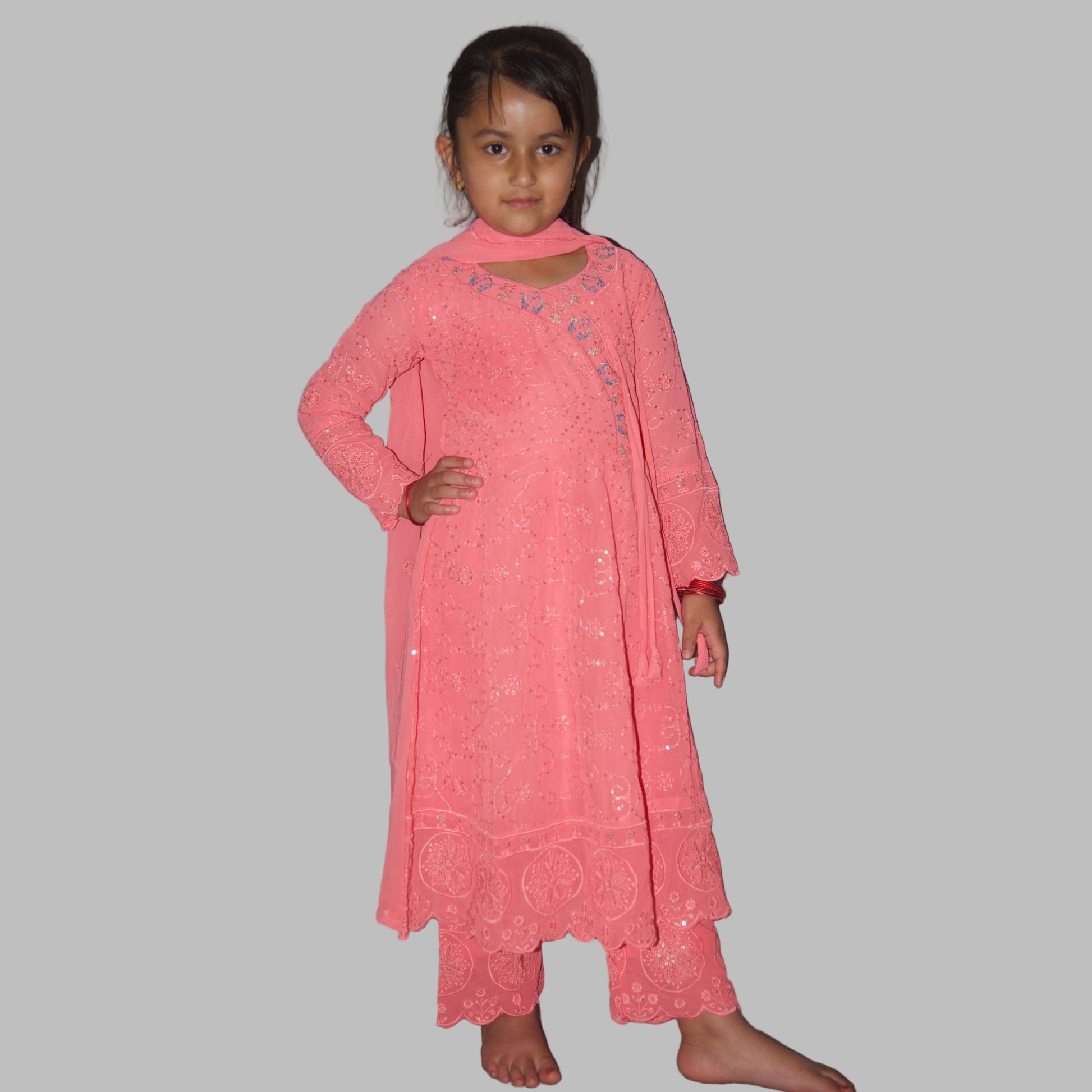 Young girl wearing a pink traditional outfit against a plain background
