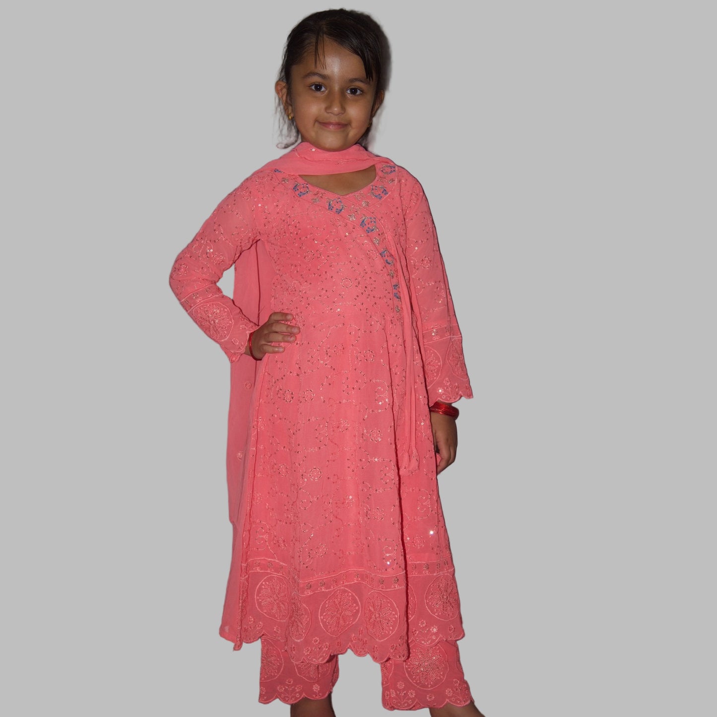 Young girl wearing a pink traditional outfit against a plain background