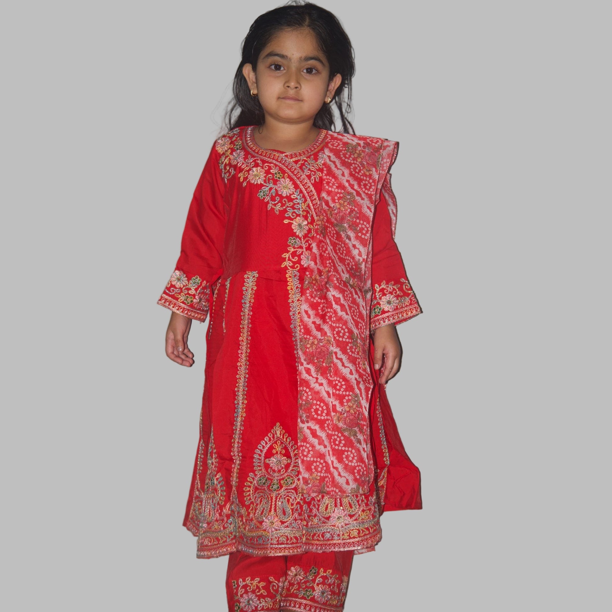 Child wearing a red embroidered traditional outfit against a plain background