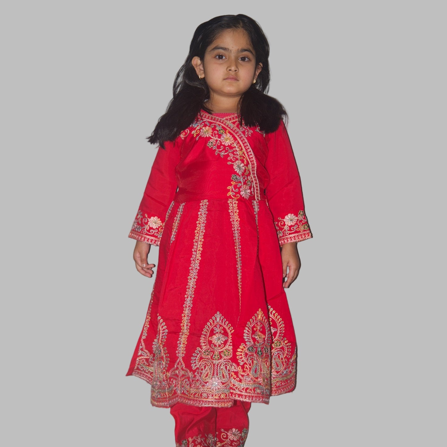 Young girl wearing a red embroidered traditional outfit against a plain background