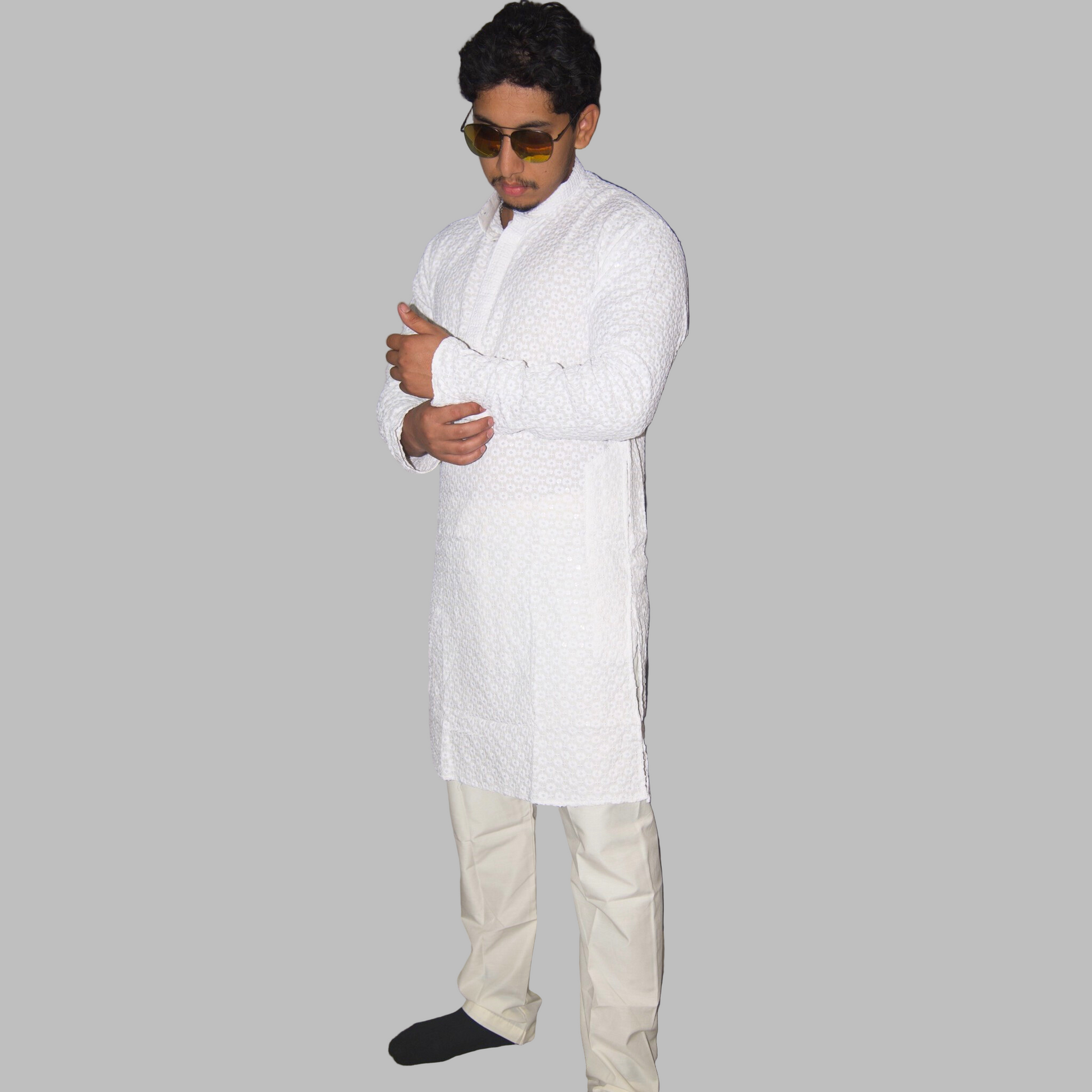 Person wearing a white kurta with beige pants against a plain background