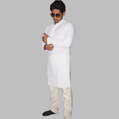 Person wearing a white kurta with beige pants against a plain background