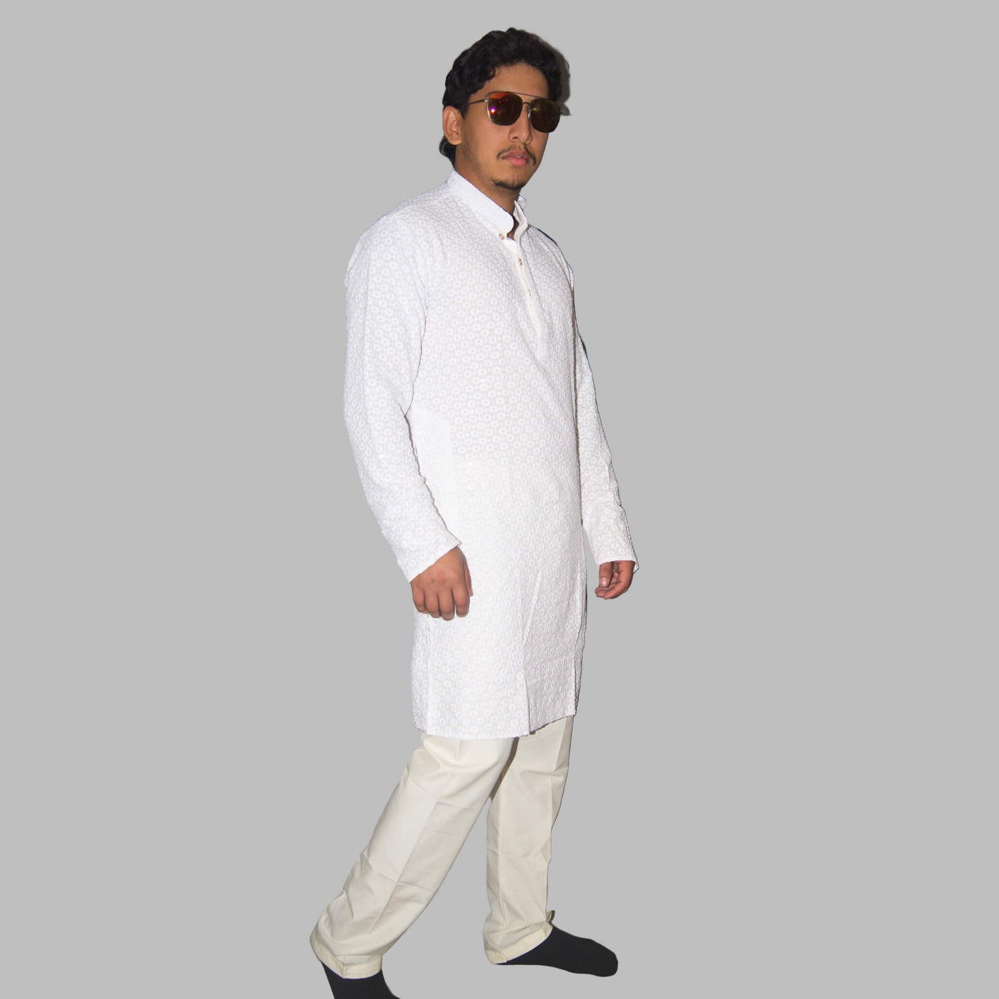 Man wearing a white kurta with beige pants against a plain background
