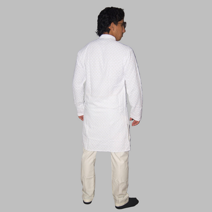 Person wearing a white kurta and beige pants against a plain background