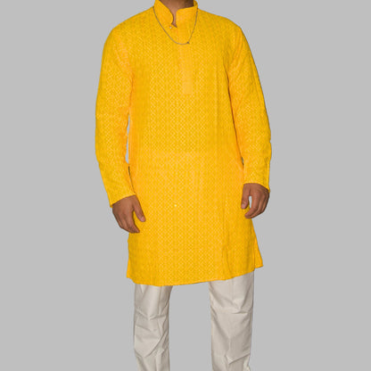 Person wearing a yellow kurta with white pants against a gray background