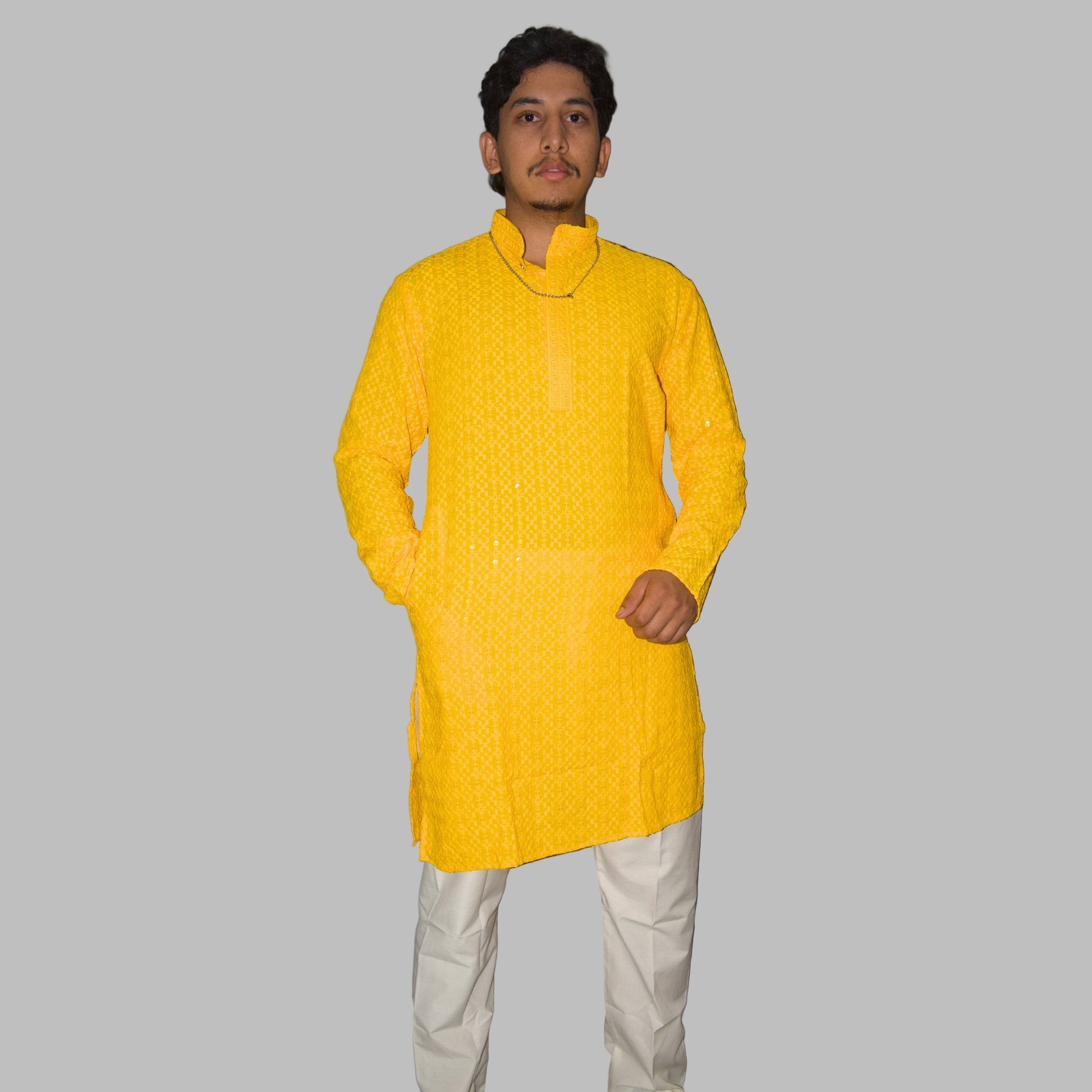 Person wearing a bright yellow kurta with white pants against a plain background