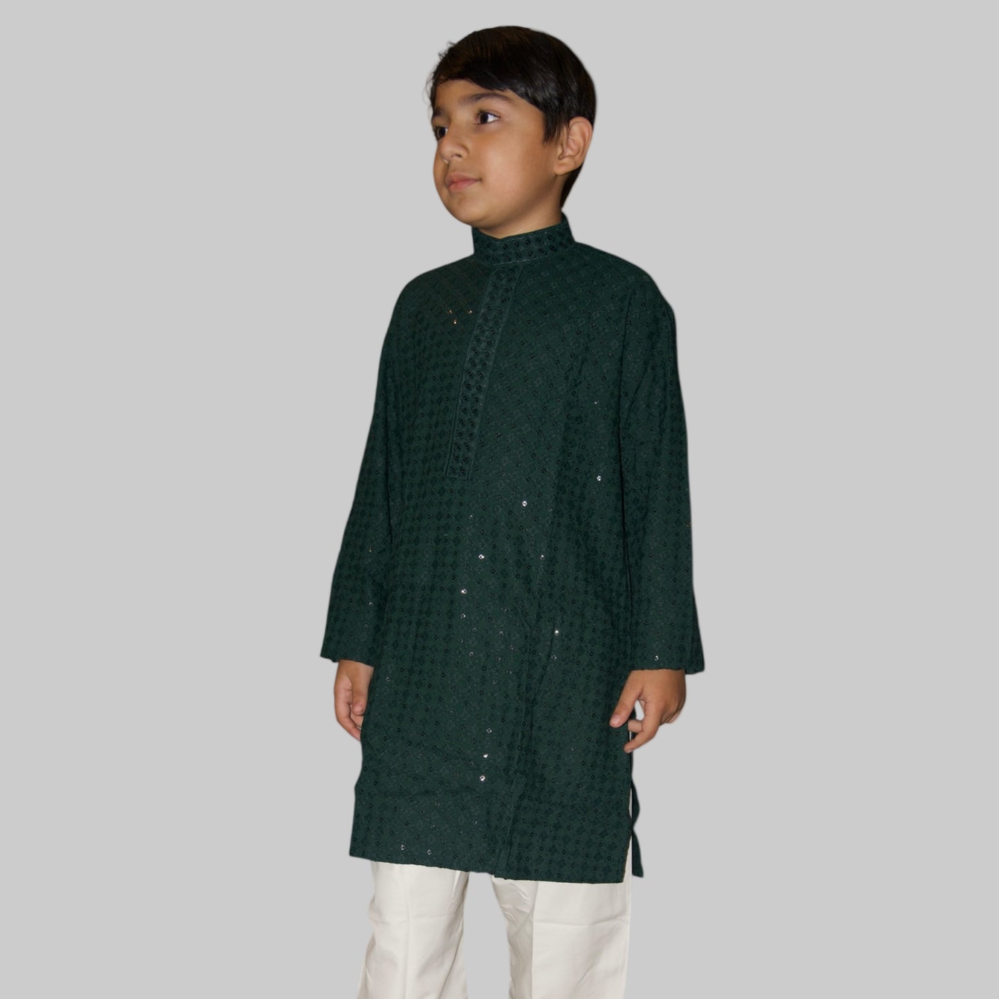 Child wearing a dark green kurta with white pants on a white background