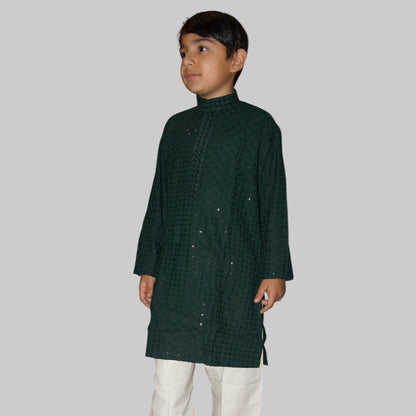 Child wearing a dark green kurta with white pants on a white background