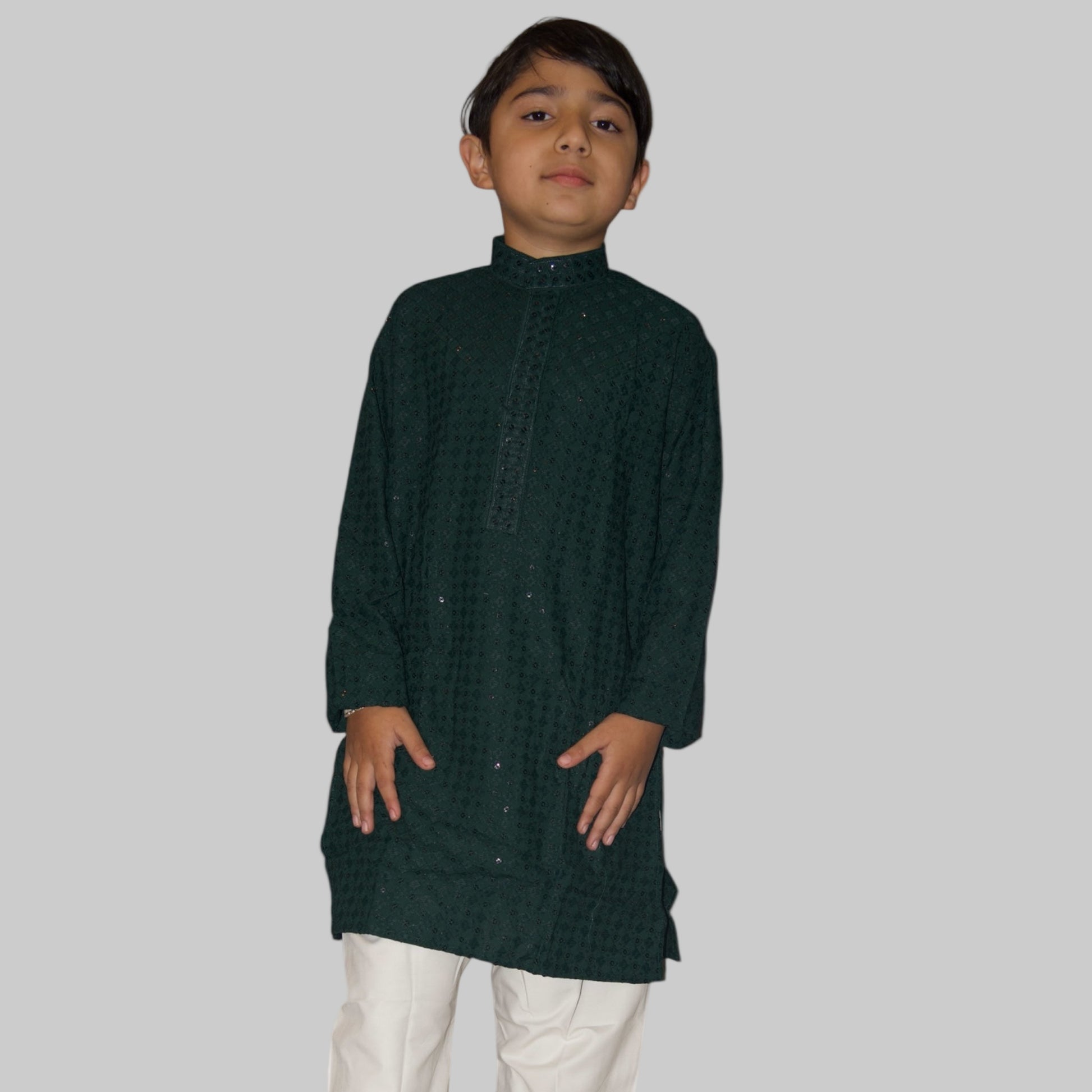 Child wearing a dark green kurta with white pants on a white background
