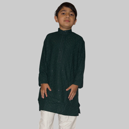 Child wearing a dark green kurta with white pants on a white background