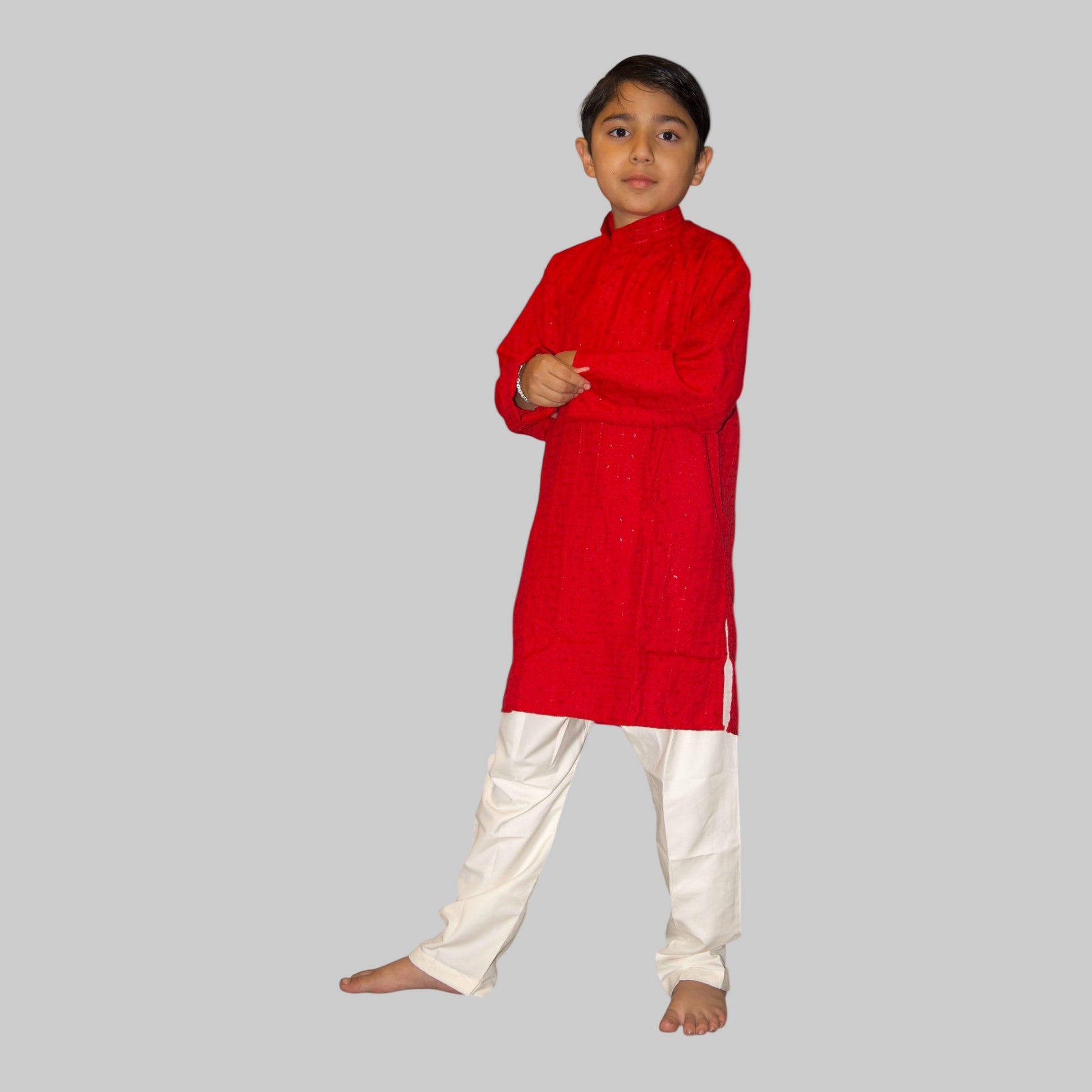 Child wearing a red kurta with white pants on a white background
