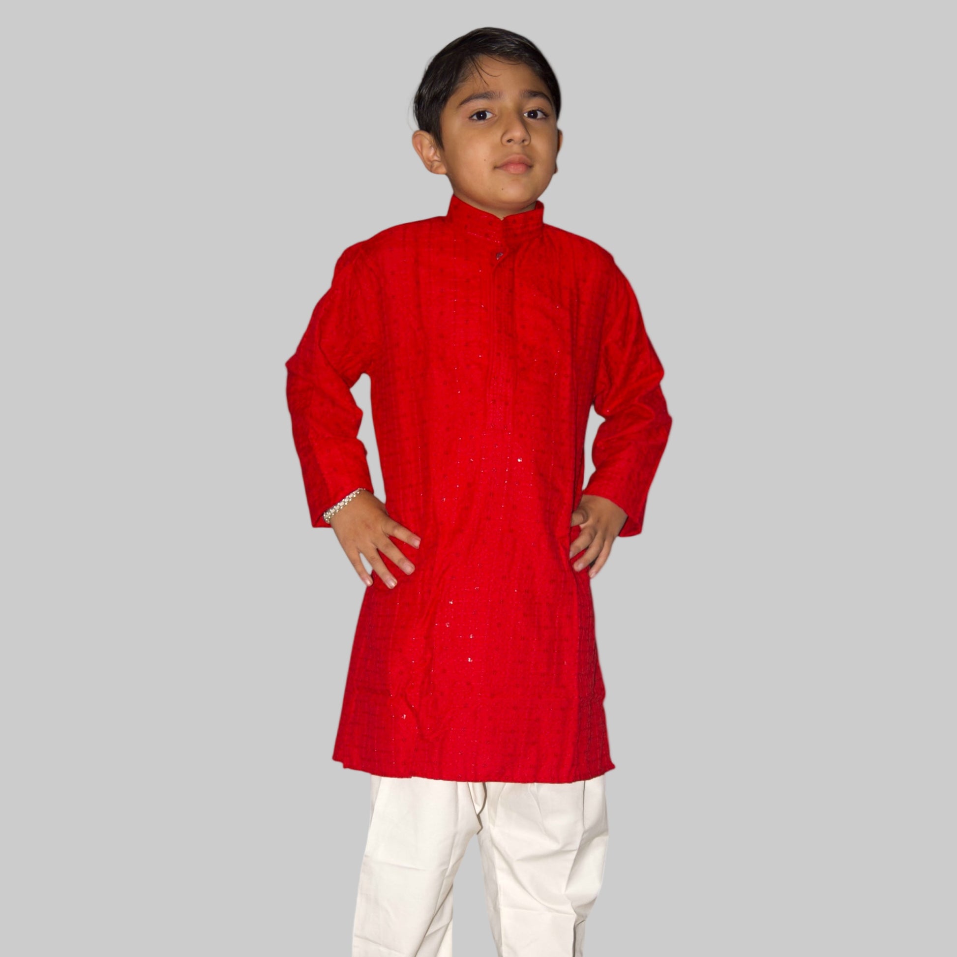 Child wearing a red kurta with white pants on a white background