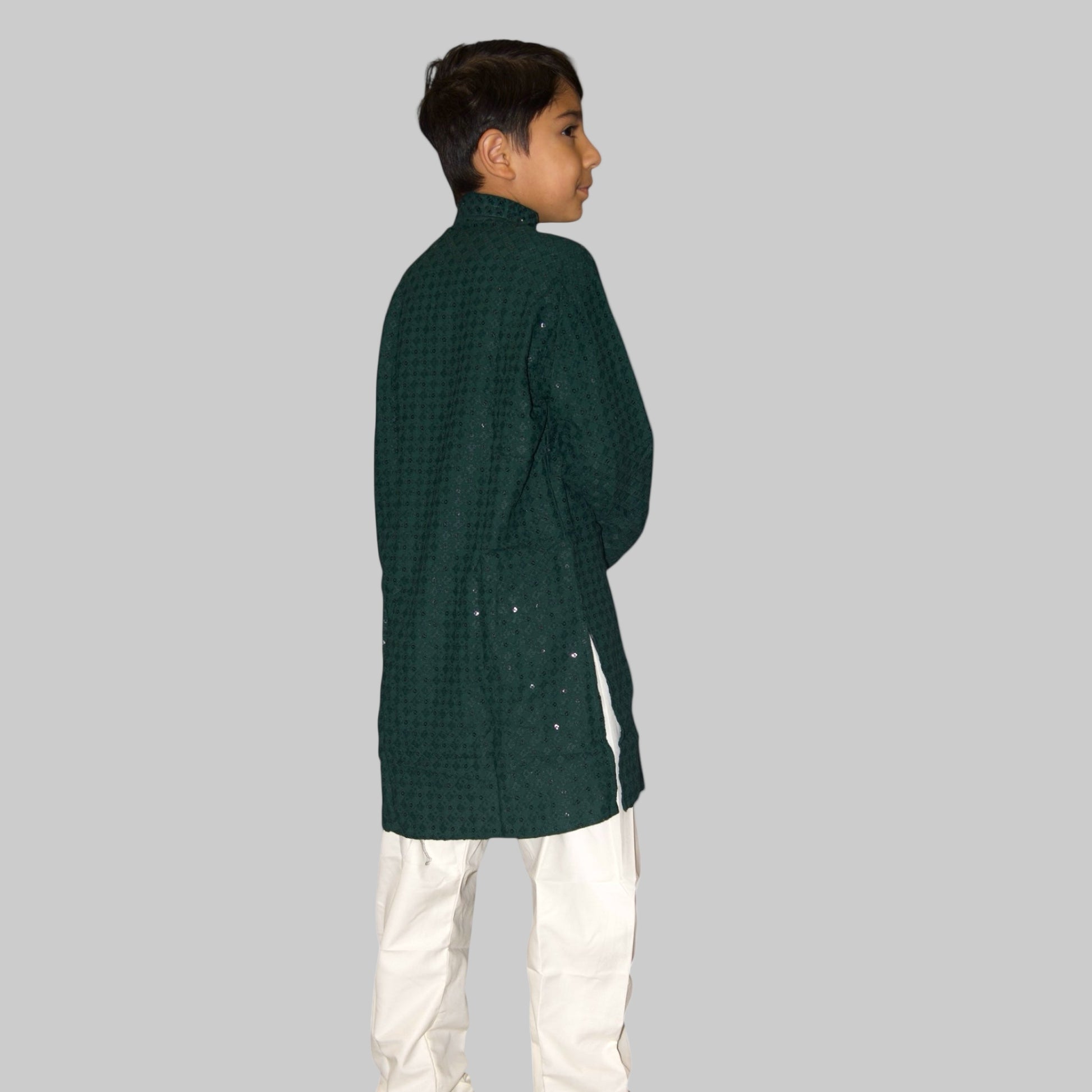 Child wearing a green checkered kurta with white pants on a white background