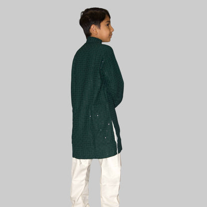Child wearing a green checkered kurta with white pants on a white background