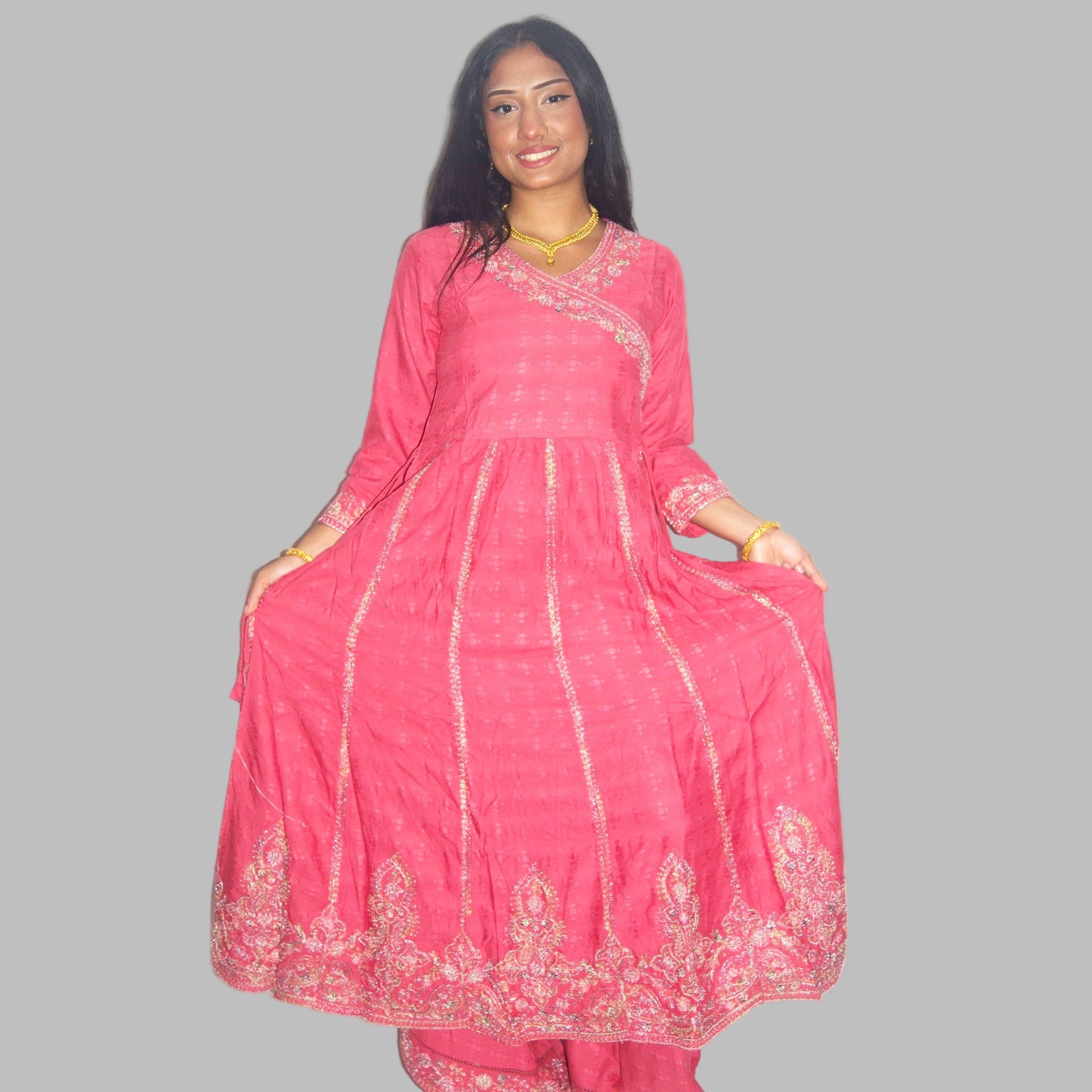 Woman wearing a pink traditional outfit with gold embroidery on a white background