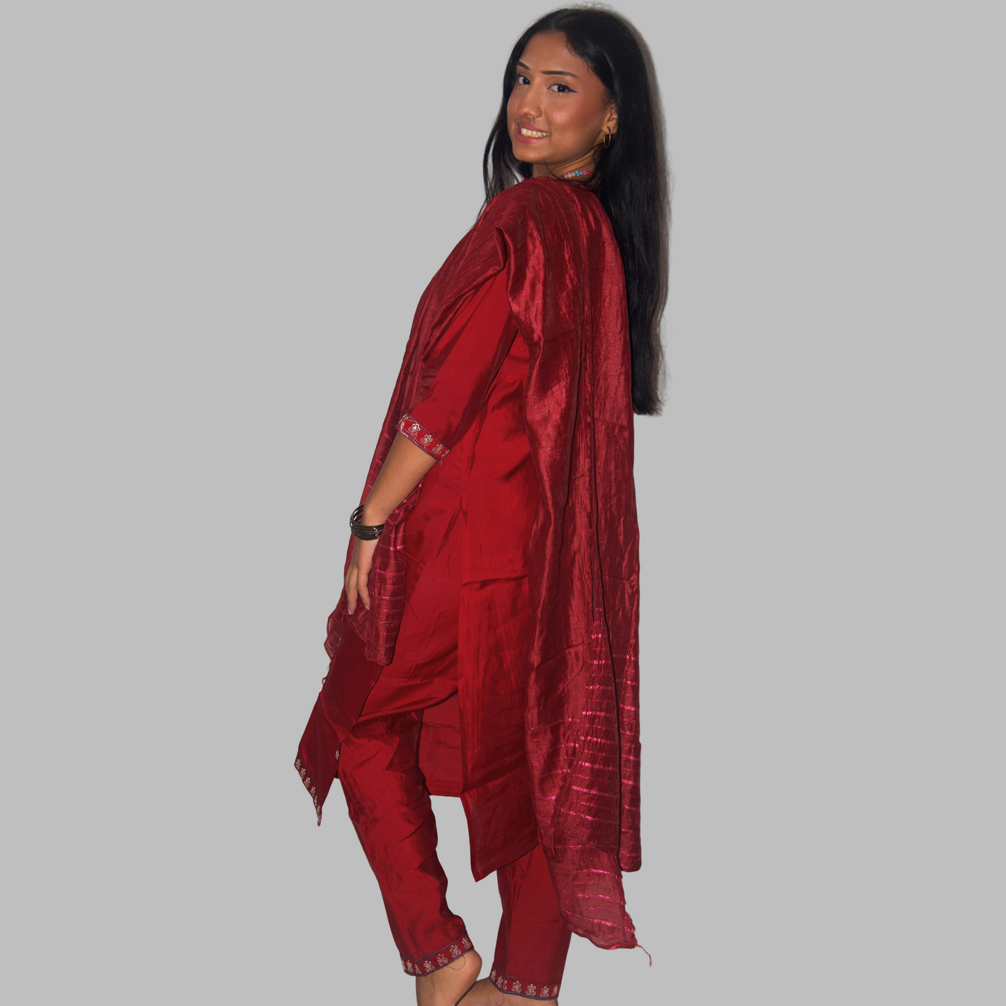Woman wearing a red traditional outfit against a white curtain