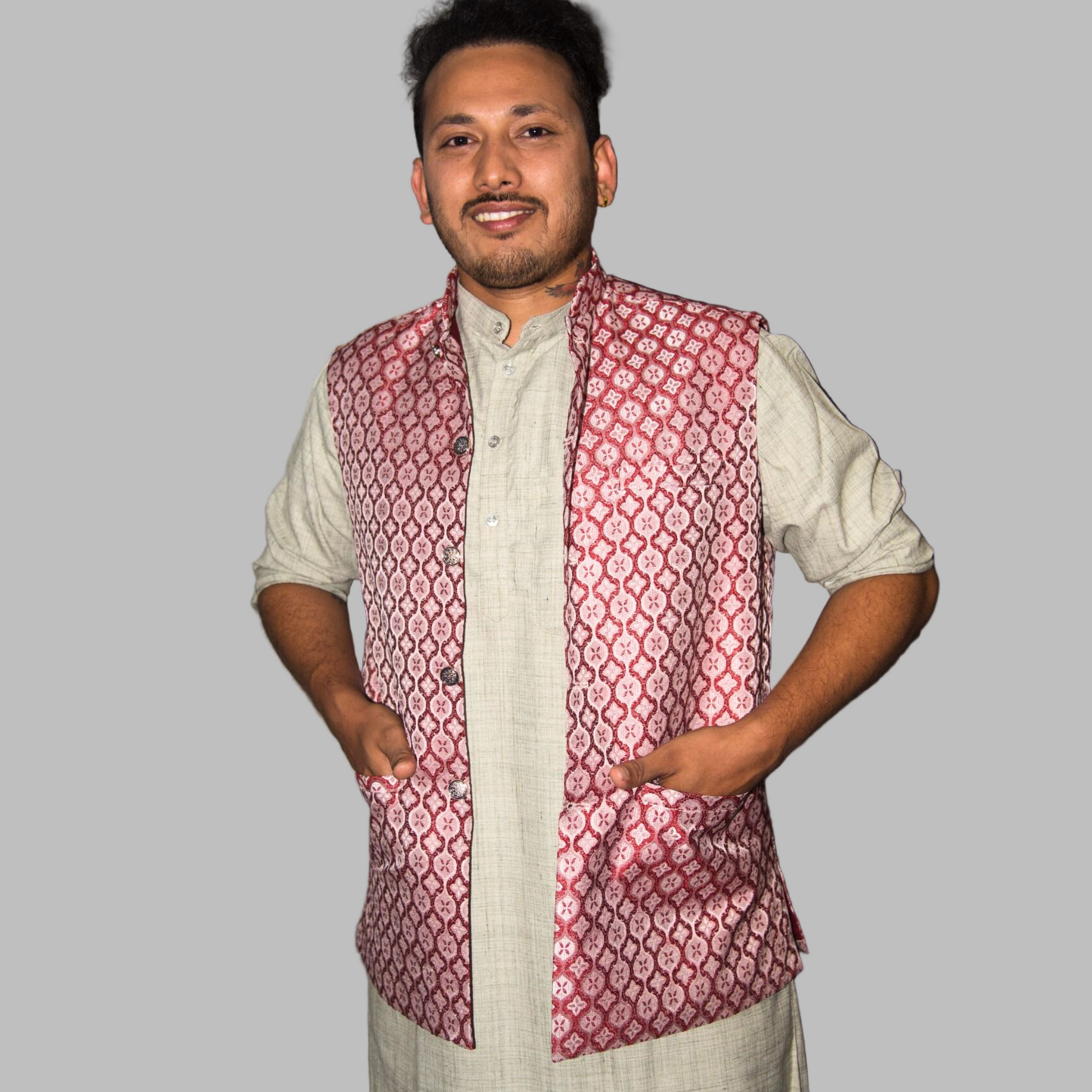 Man wearing a patterned vest over a light shirt against a plain background