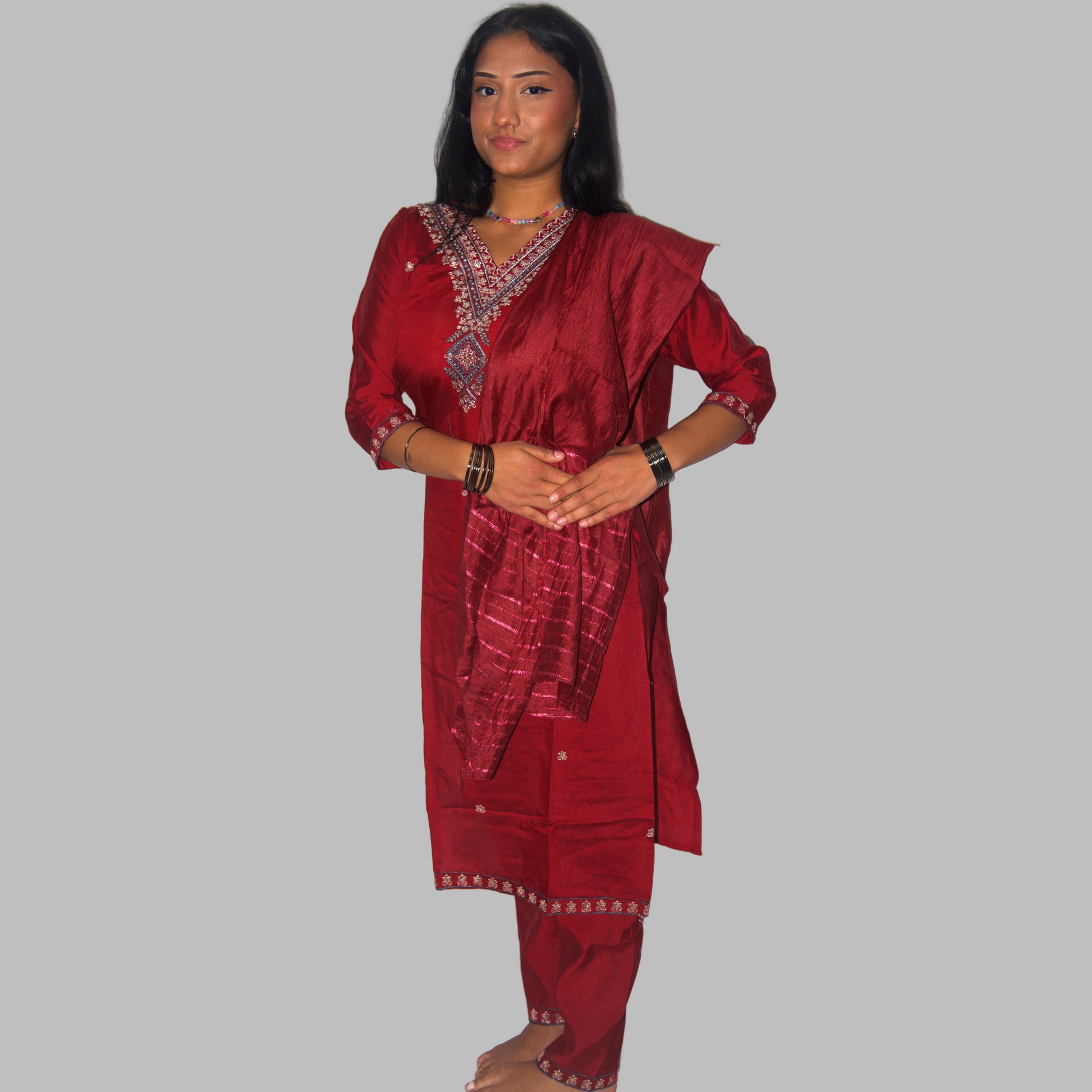 Woman wearing a red traditional outfit with intricate patterns on a white background