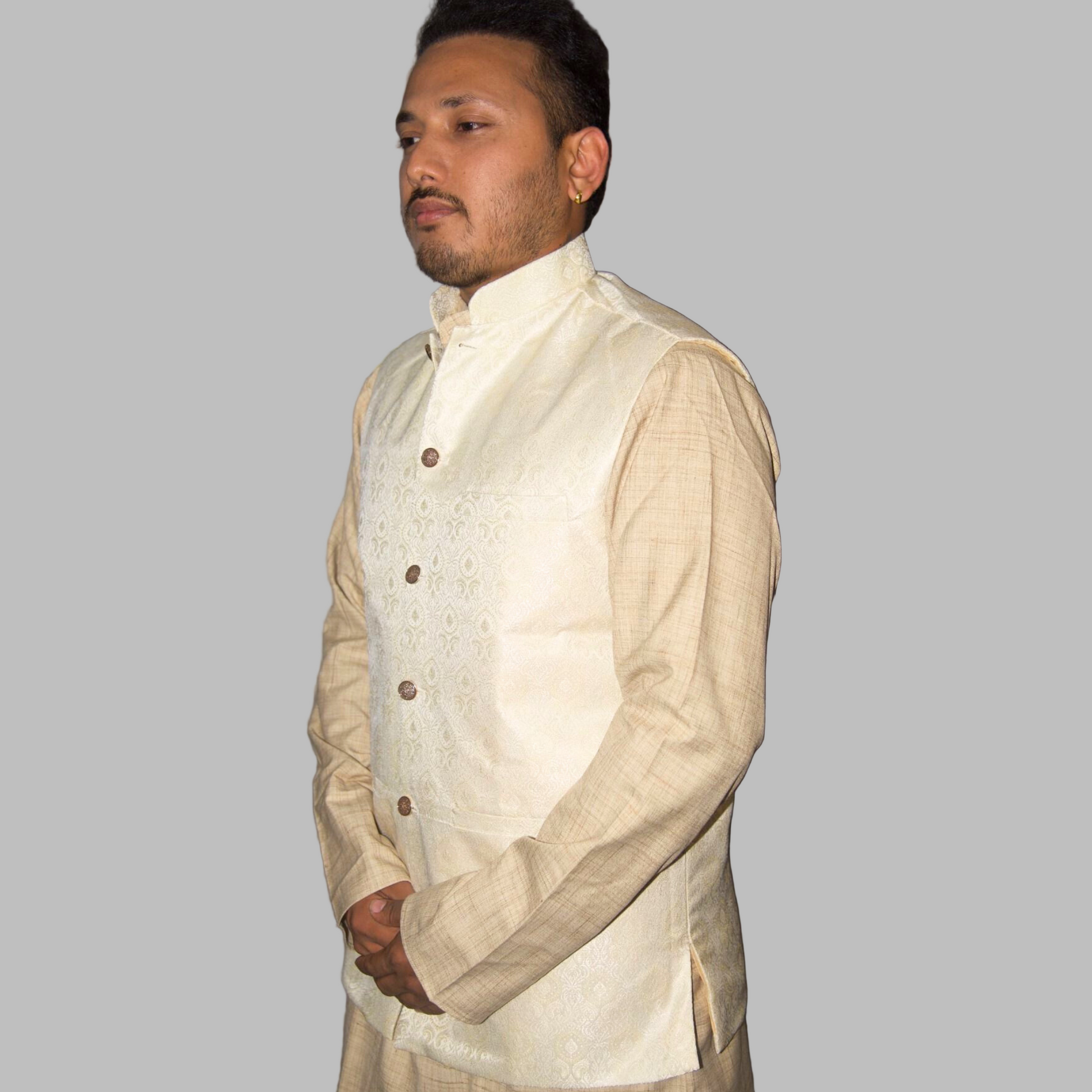 Man wearing a cream-colored traditional outfit with a vest against a plain background