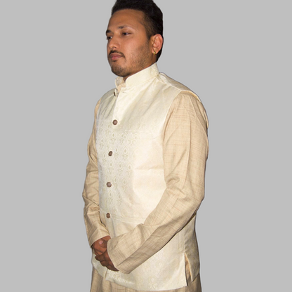 Man wearing a cream-colored traditional outfit with a vest against a plain background