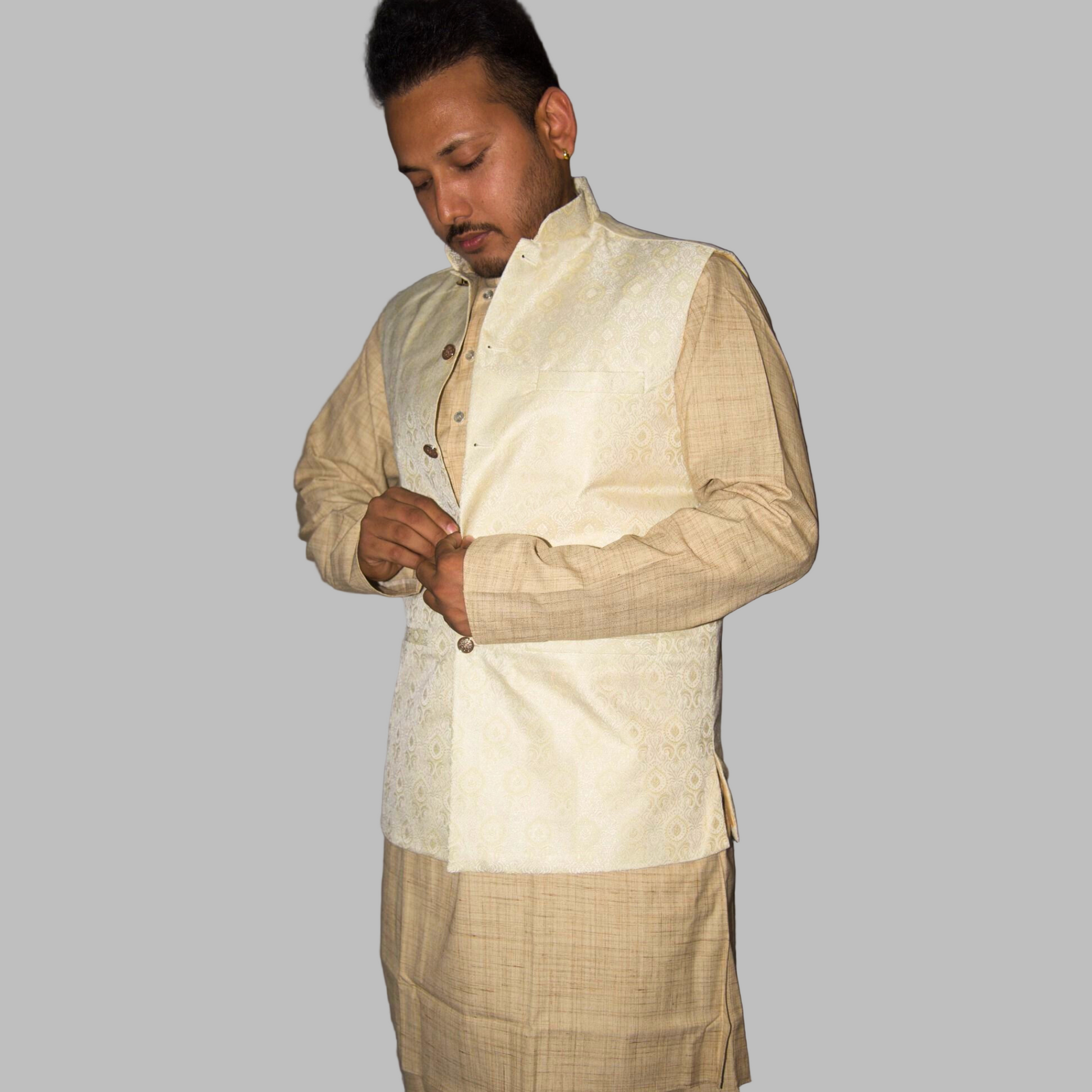 Man wearing a traditional beige kurta with a vest against a gray background