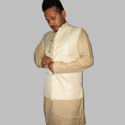 Man wearing a traditional beige kurta with a vest against a gray background