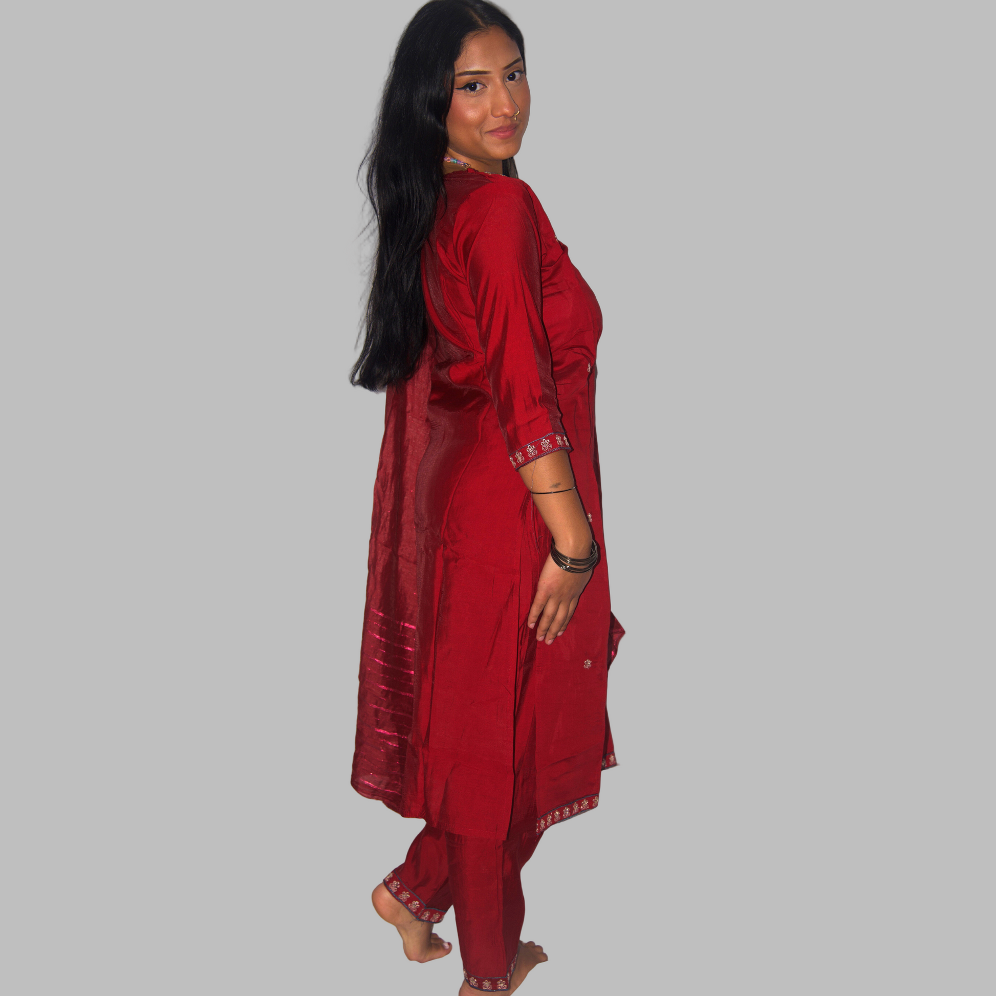 Woman wearing a red traditional outfit against a white curtain