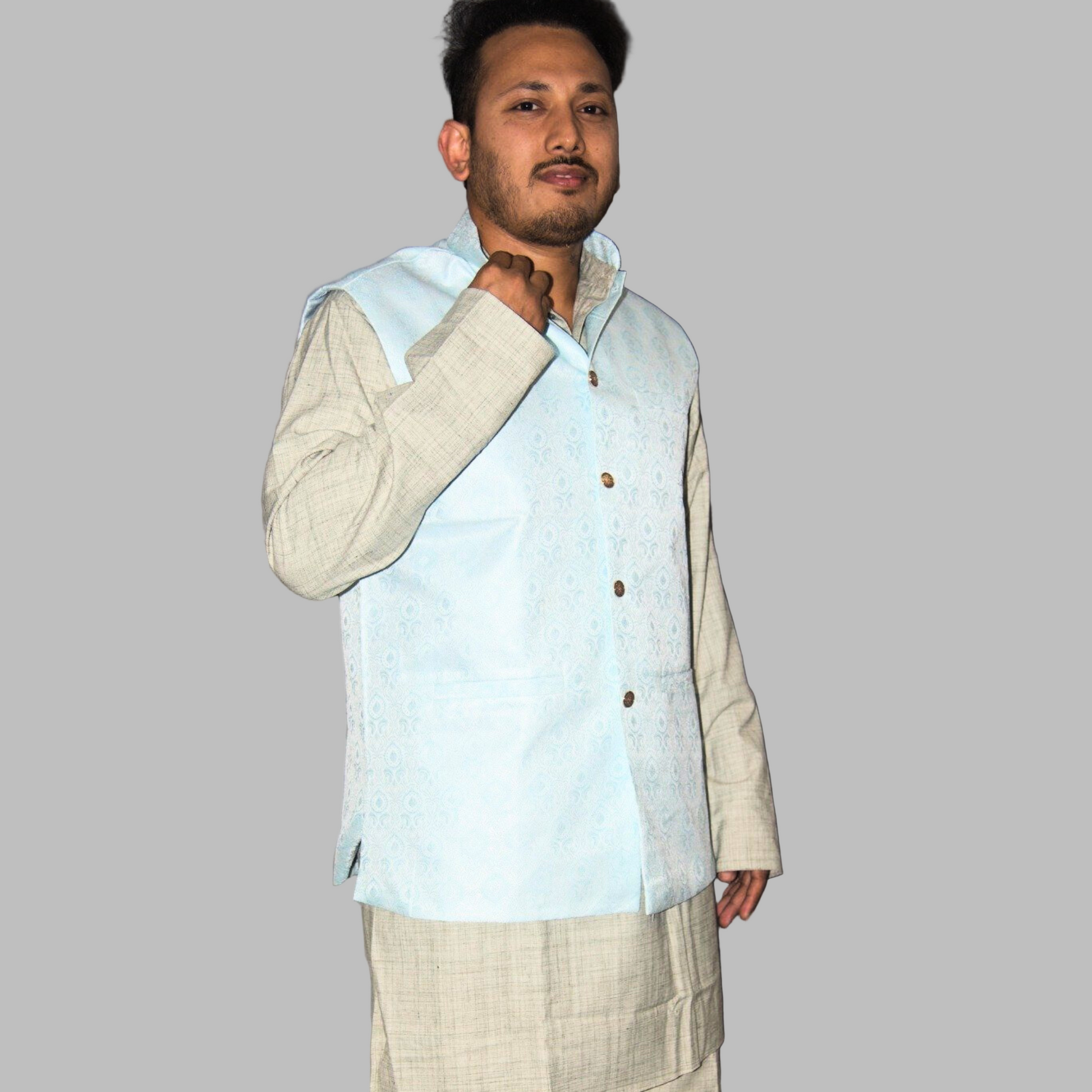 Man wearing a light blue vest over a beige shirt against a plain background